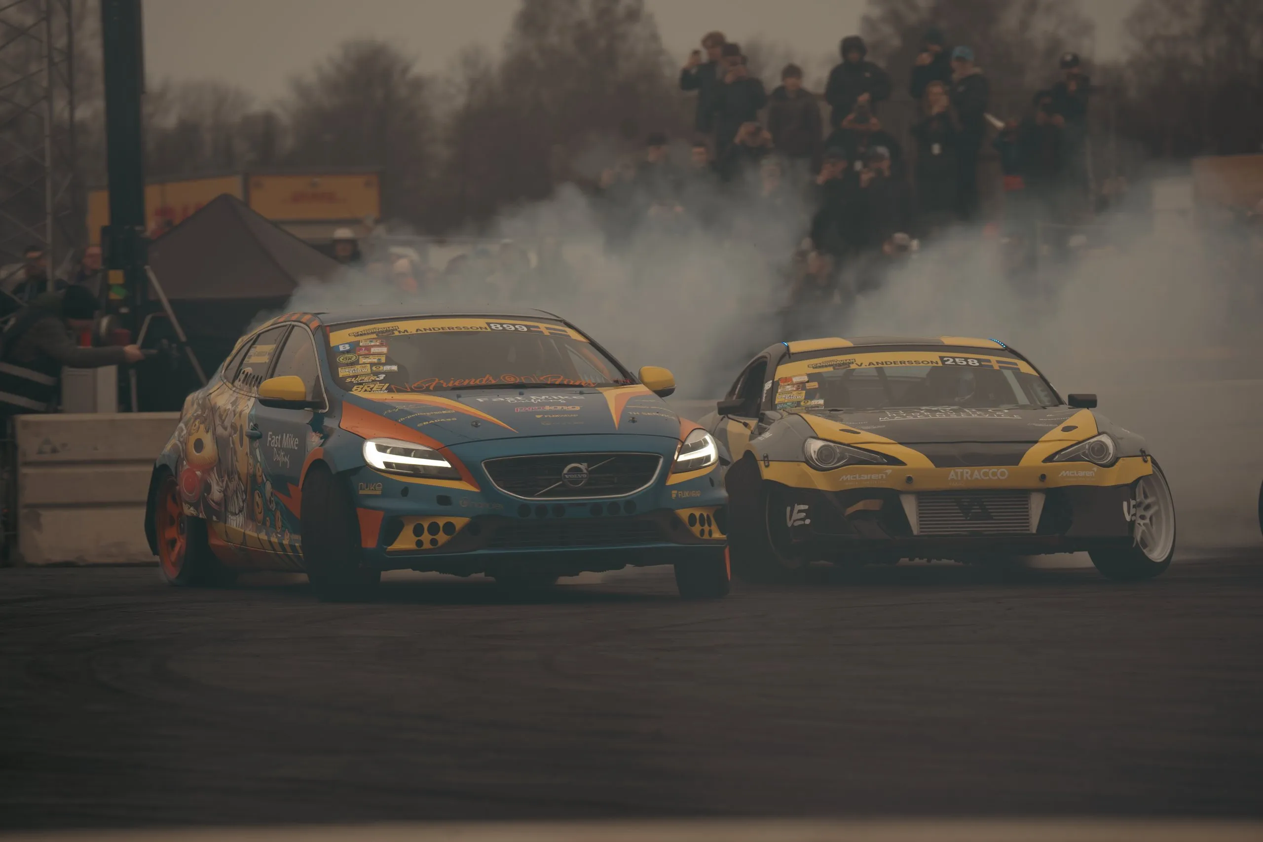 Två driftbilar sida vid sida i däckrök