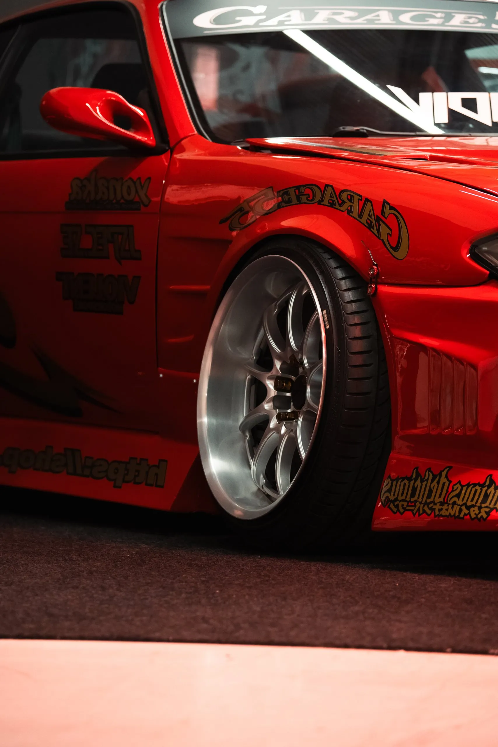 Röd driftbil på polerade fälgar i hallen, Custom Motor Show 2024