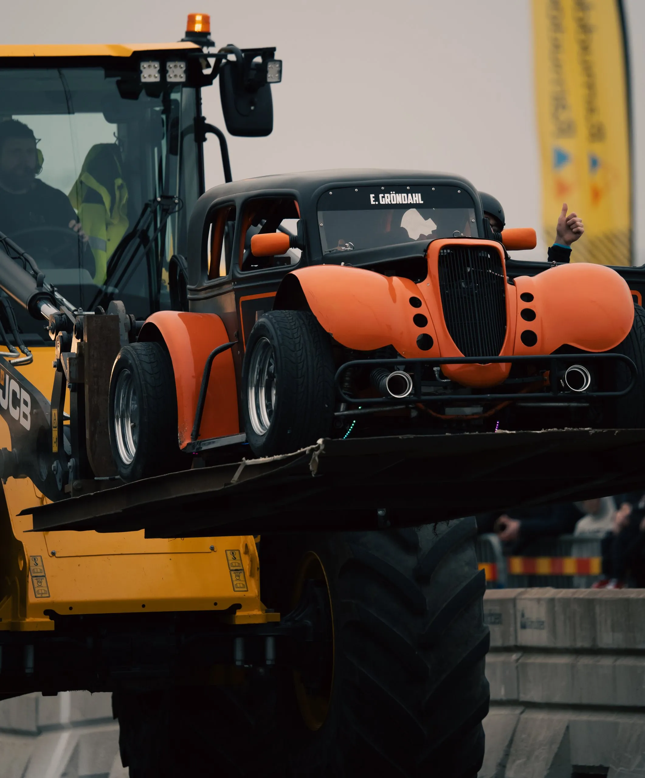 Orange och svart hot rod lyfts av en hjullastare