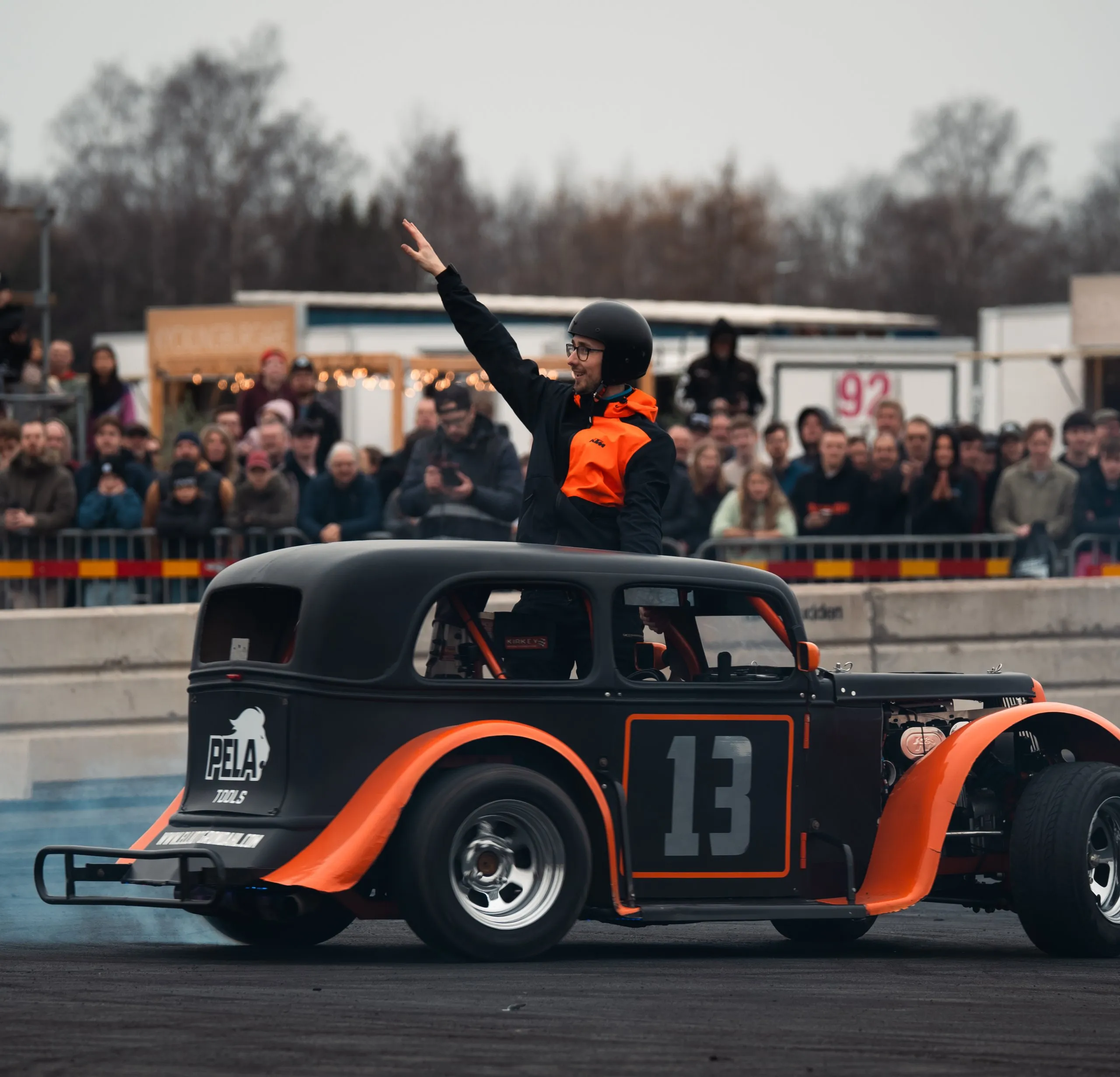 Föraren av hot rod nummer 13 hälsar på publiken