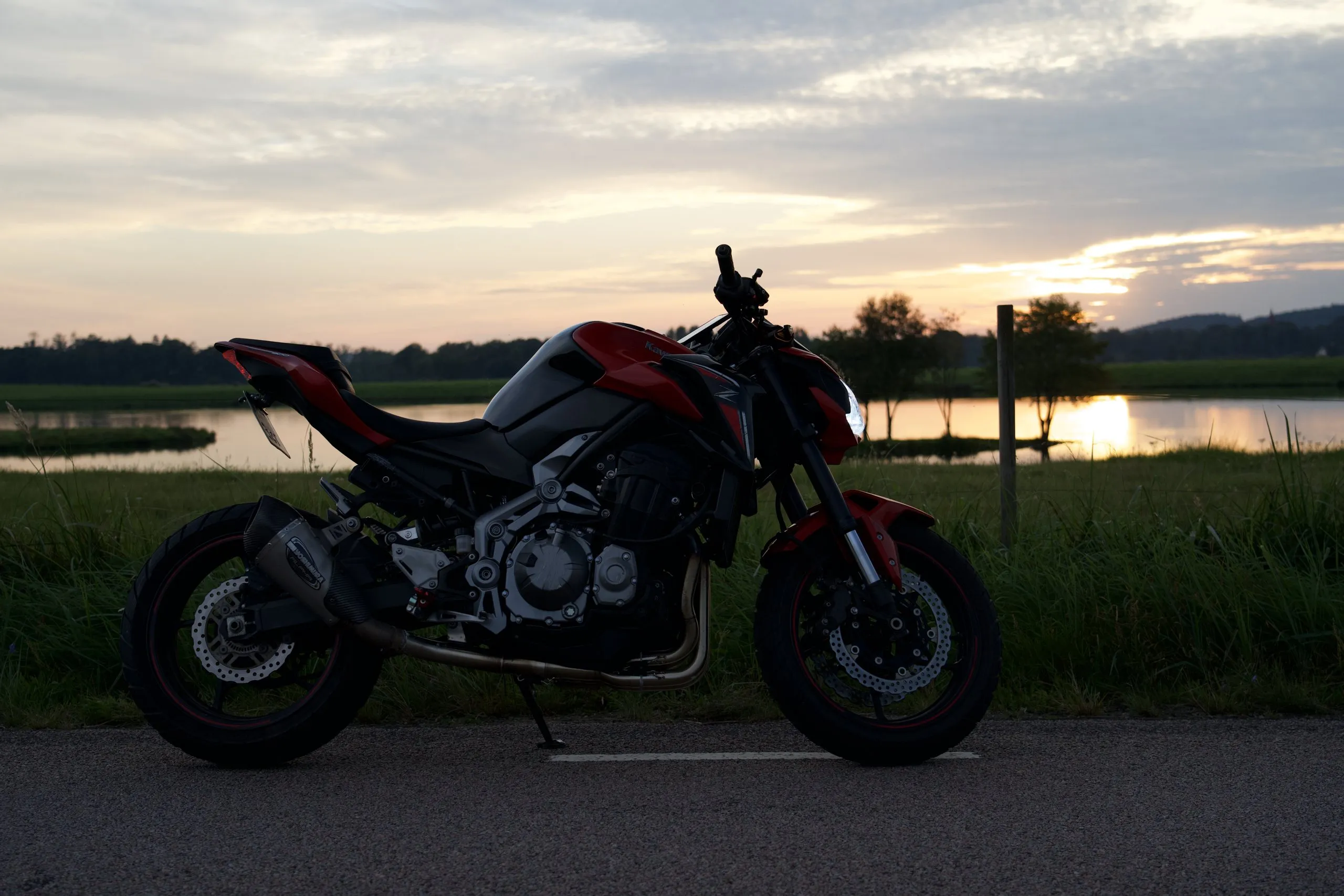 Röd Kawasaki Z900 vid en sjö i solnedgången